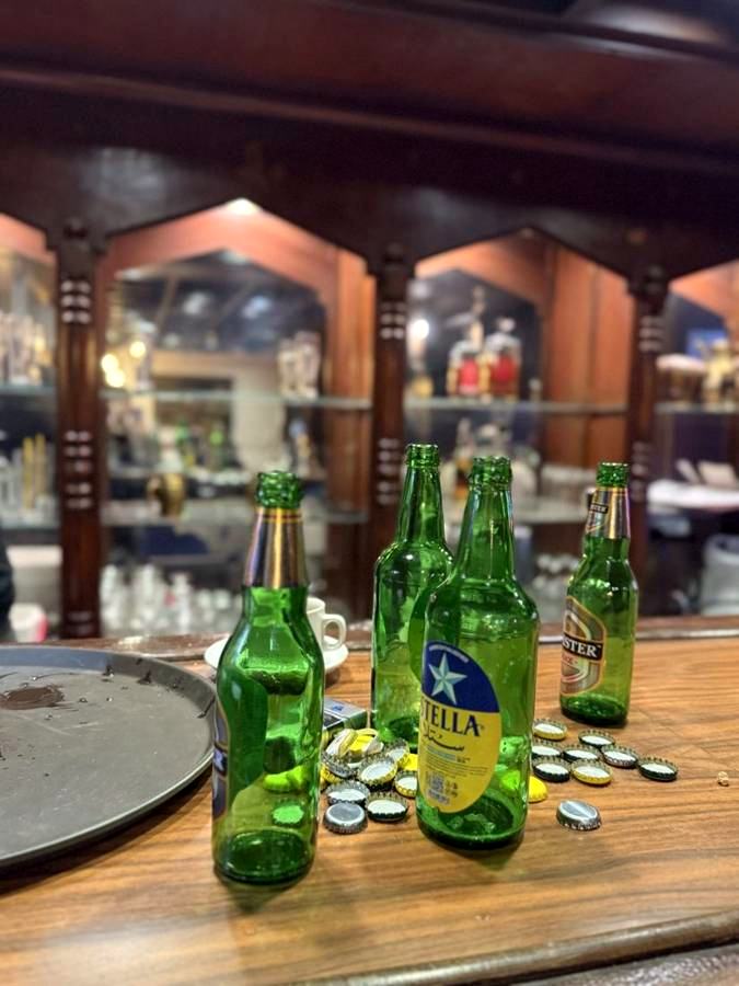 Green beer bottles and bottle caps on the wooden bar