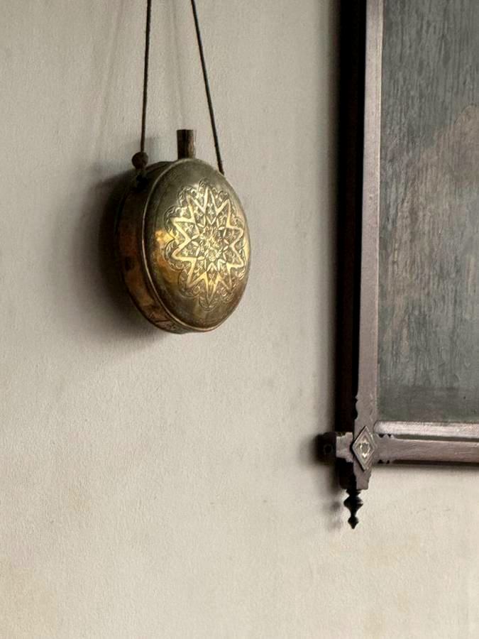 Engraved brass ornament hanging on a plaster wall