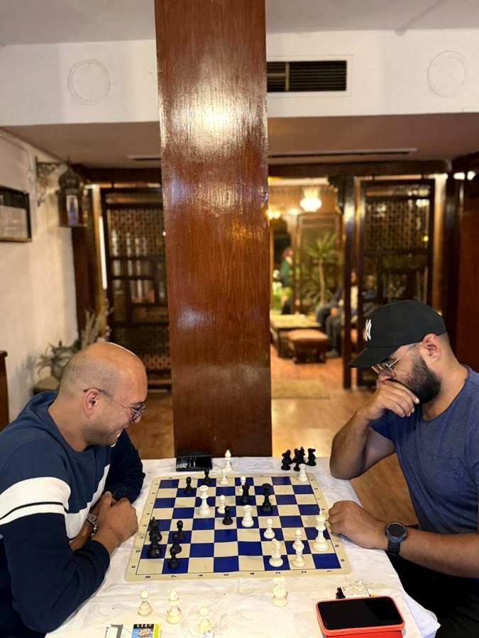 Two friends playing chess at a table in the hotel