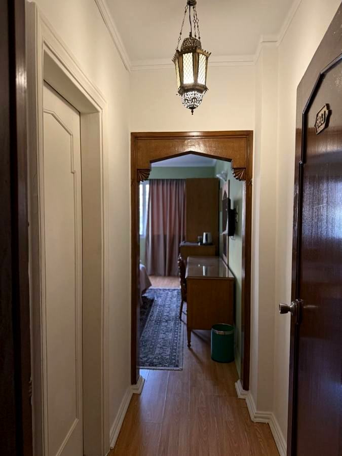 Guest corridor with wooden doors, a hanging lantern and an arched doorway into a room