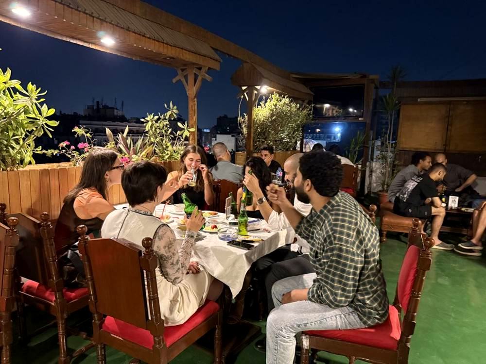 A long table of friends having dinner on the rooftop at night