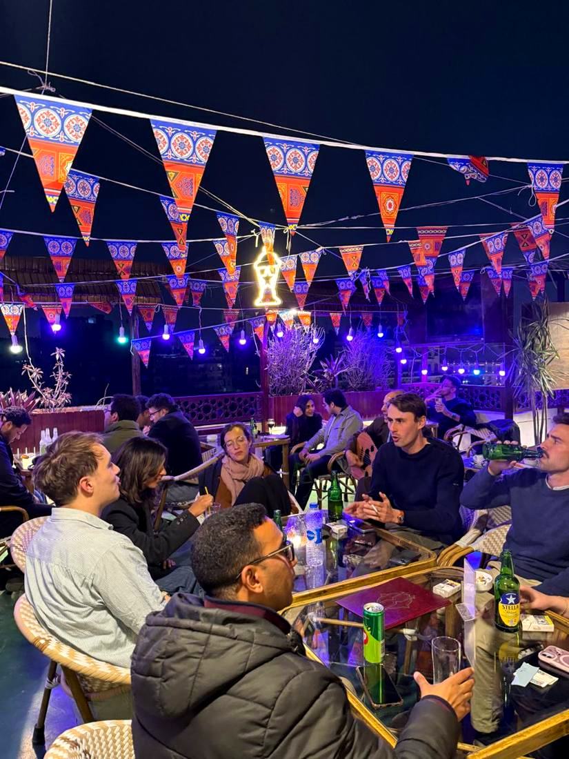 A busy rooftop table at night under strings of lights and bunting