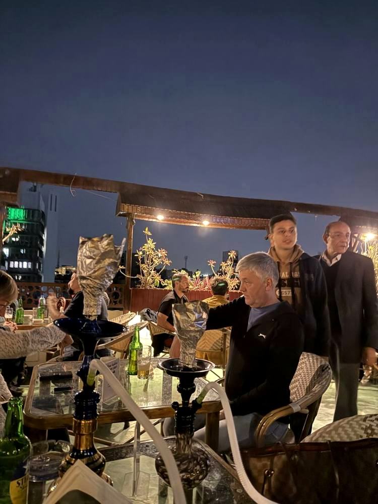 Friends around a table of shisha pipes on the rooftop at dusk