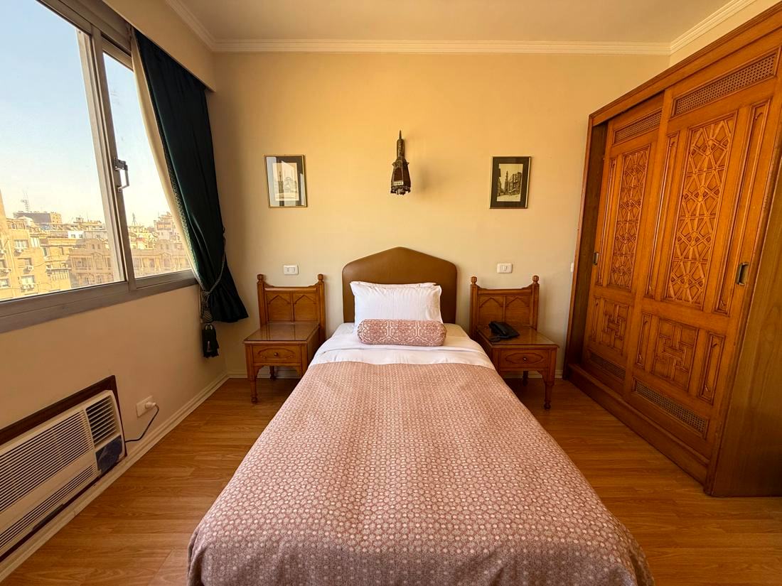 Single room with one bed, carved wooden wardrobe and a window over Downtown