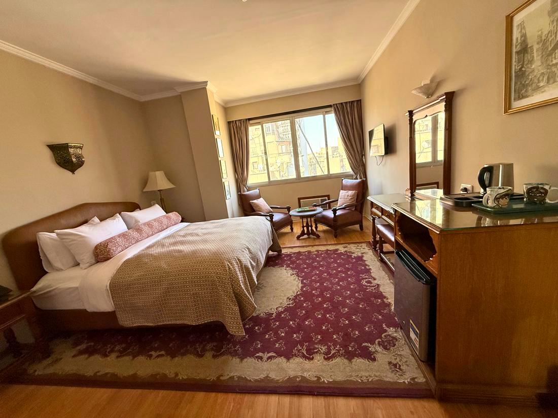 Junior suite with a double bed, armchairs, a patterned rug and a desk