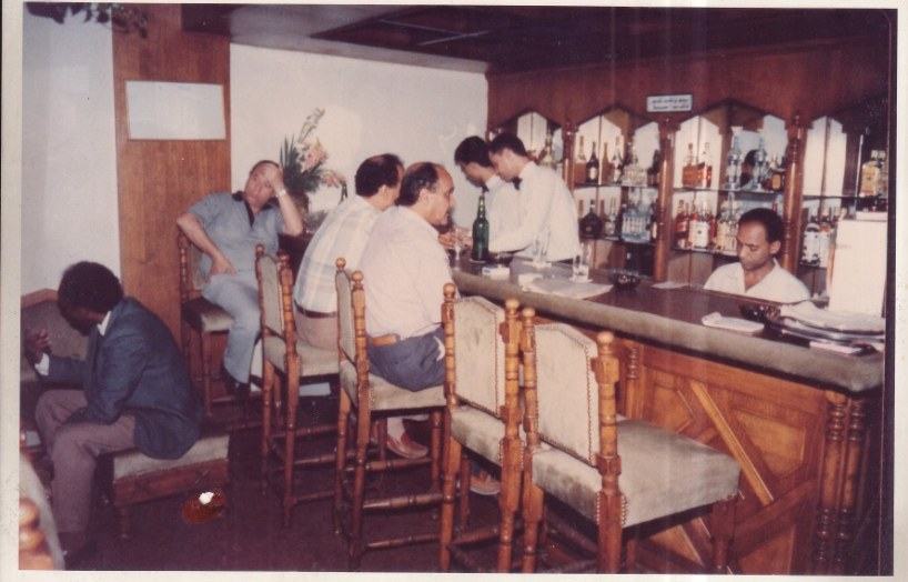 Archive photograph of the bar in the 1980s, guests on stools and the cashier behind the counter