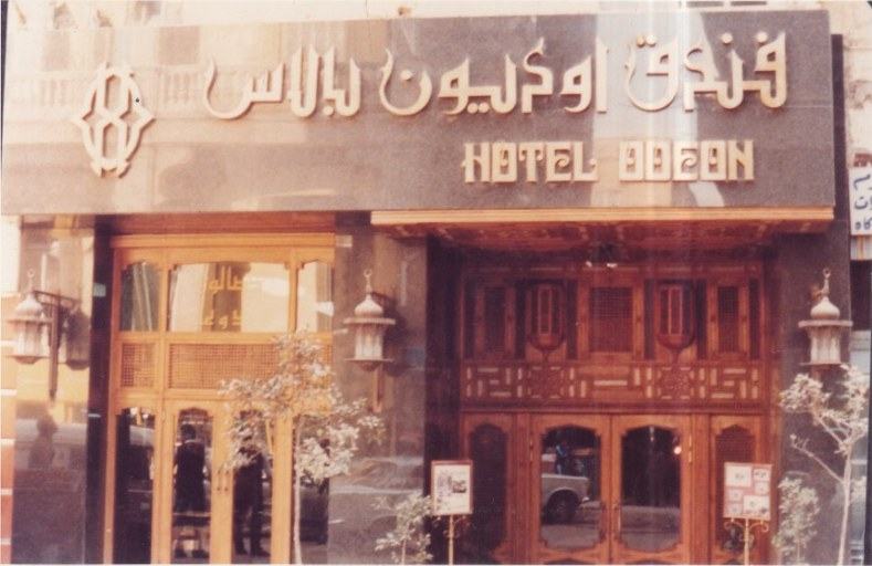 Archive photograph of the hotel entrance with its carved wooden façade and Arabic and English sign