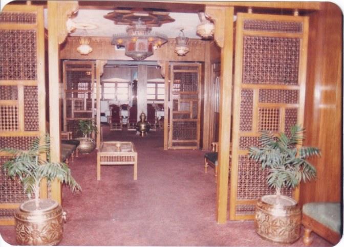 Archive photograph of the lobby with mashrabiya doors, brass planters and a carved ceiling