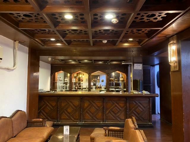 The bar today with the same arched shelves beneath a carved ceiling