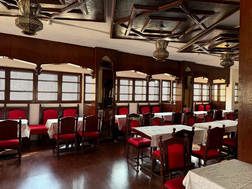 The dining room today under its carved wooden ceiling, with the same red chairs