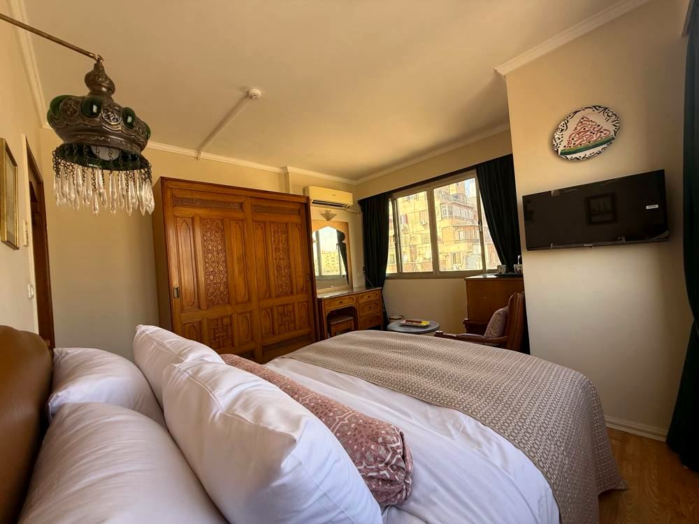 The same style of guest room today, with a carved wardrobe, brass lantern and new bedding